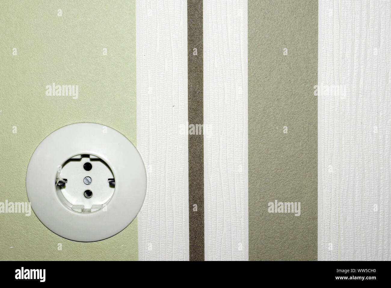 The front view of an old socket in front of a strikingly striped wallpaper, Stock Photo