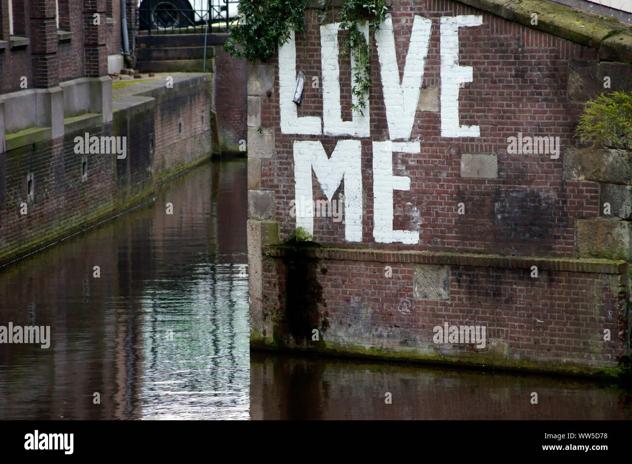 The writing Love me on a wall of a brick building at a side channel, Stock Photo