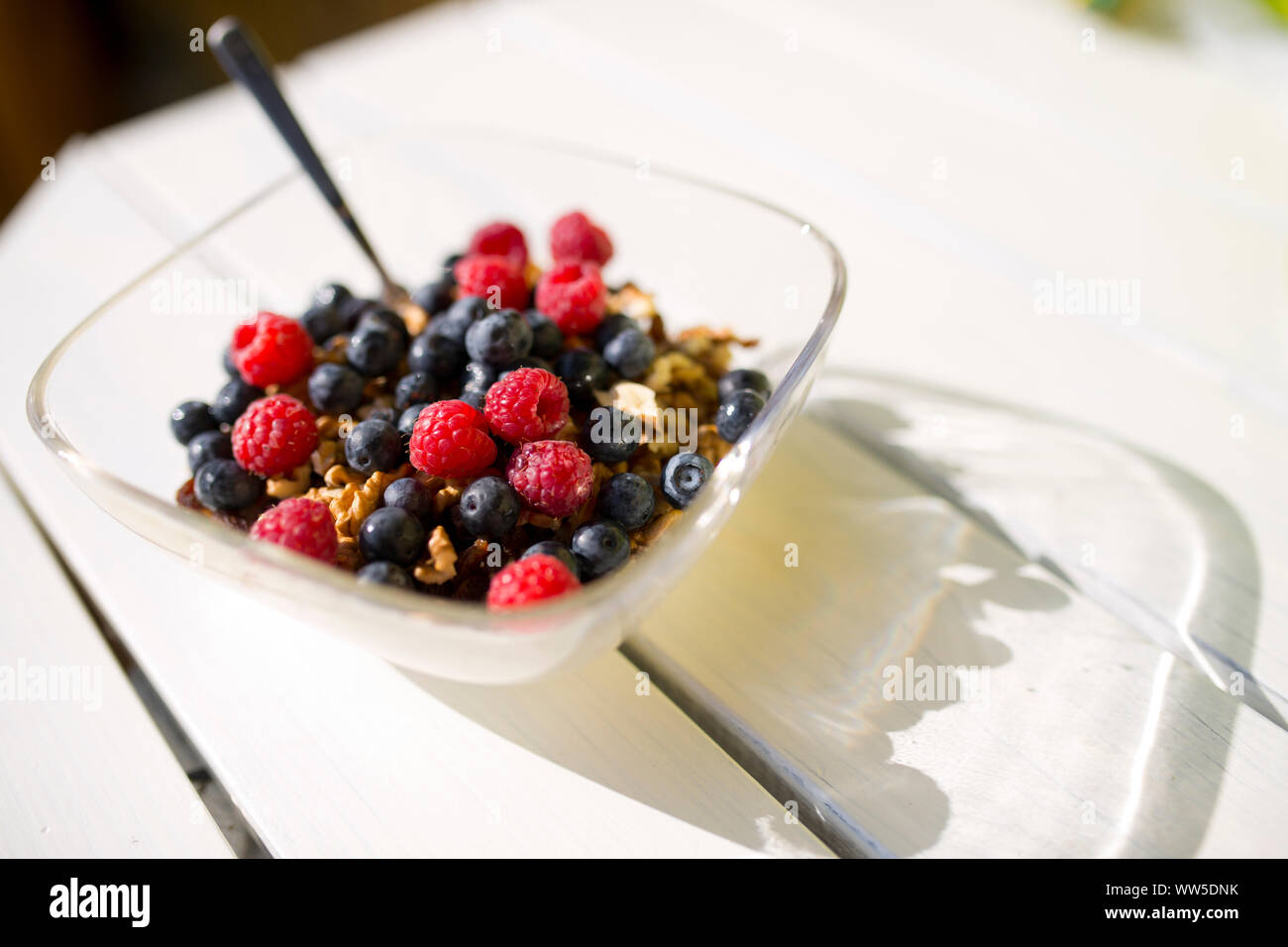 Glass bowl with raspberries and blueberries on white wooden table Stock Photo