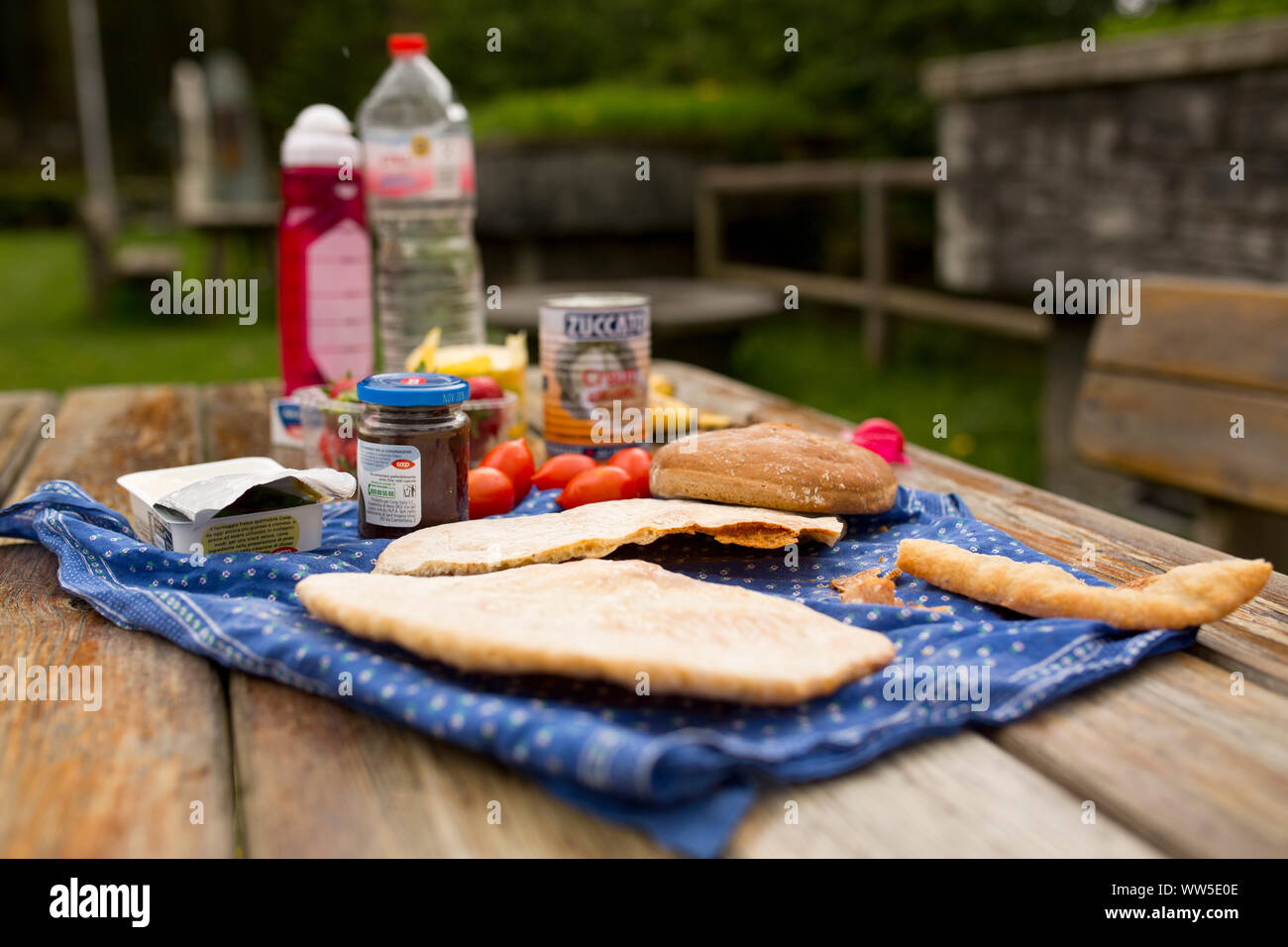 Picnic set on wooden table with bread, tomatoes and headscarf as table cloth Stock Photo
