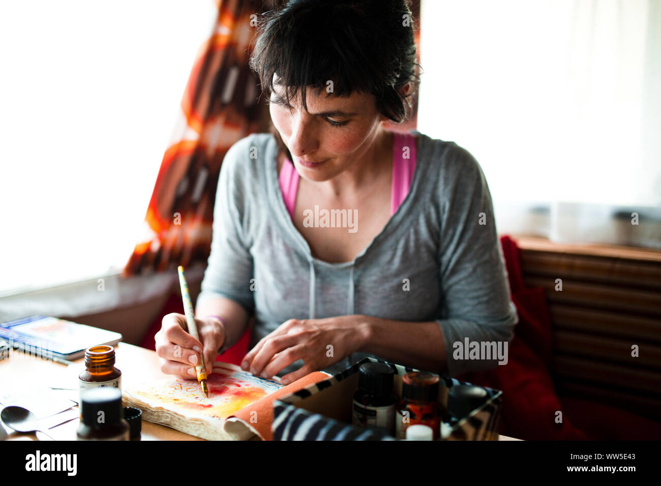 30-40 years old woman sitting in the caravan painting on paper with watercolour Stock Photo