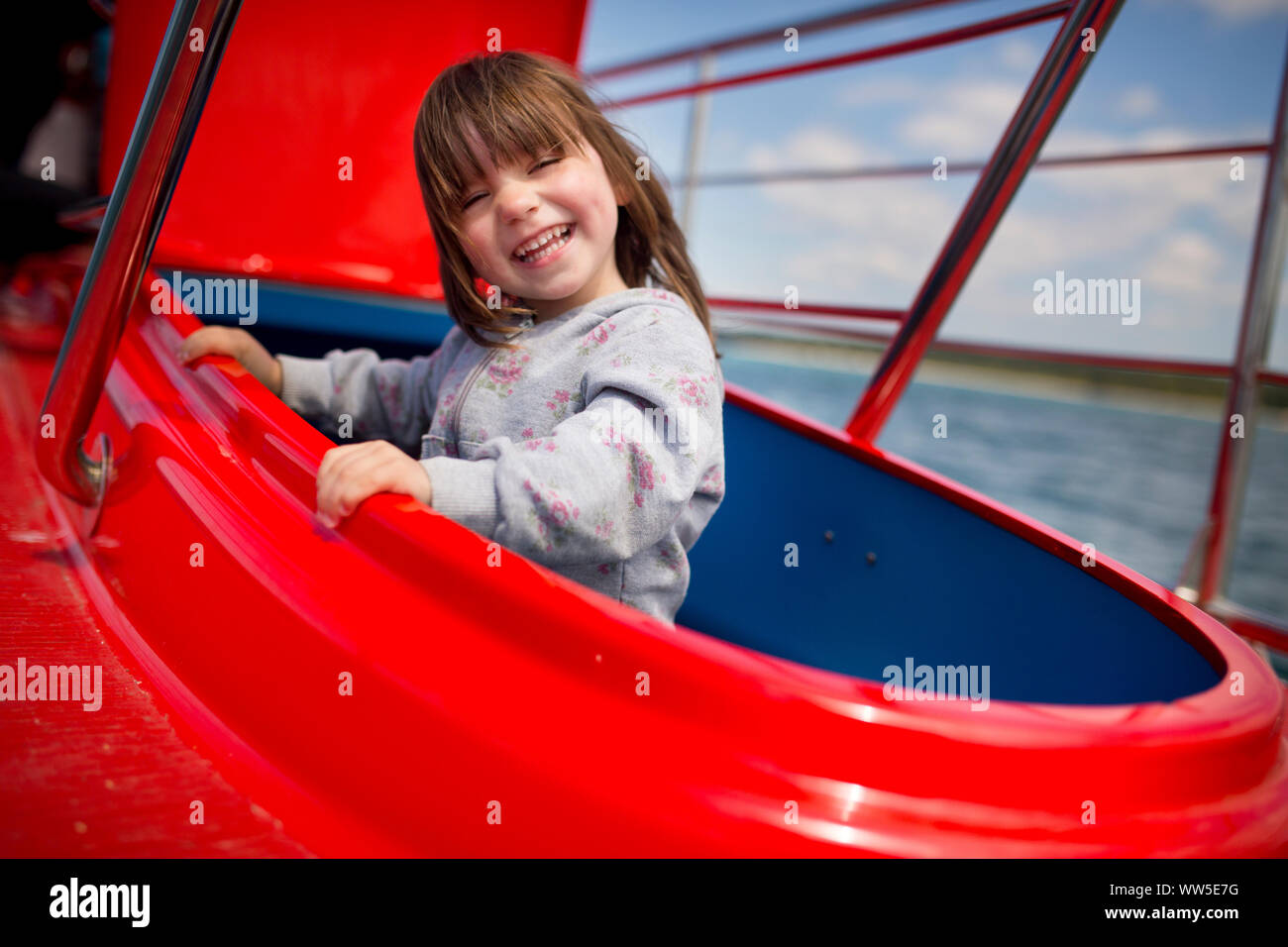 4-6 years old girl standing on a red boat, looking laughing from a hatch Stock Photo