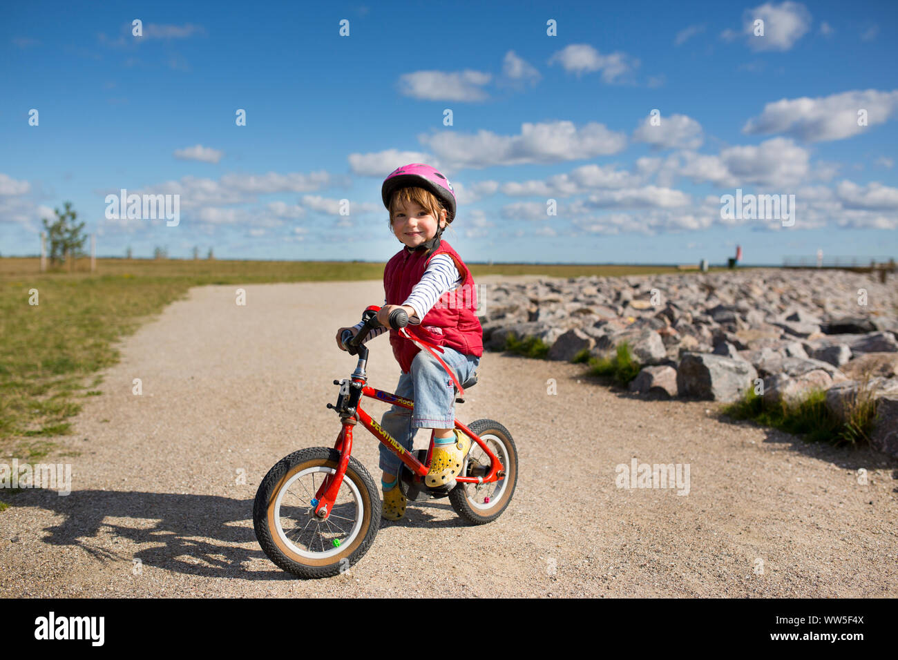 4-6 years old girl riding red children's bicycle on a way at the Baltic coast Stock Photo