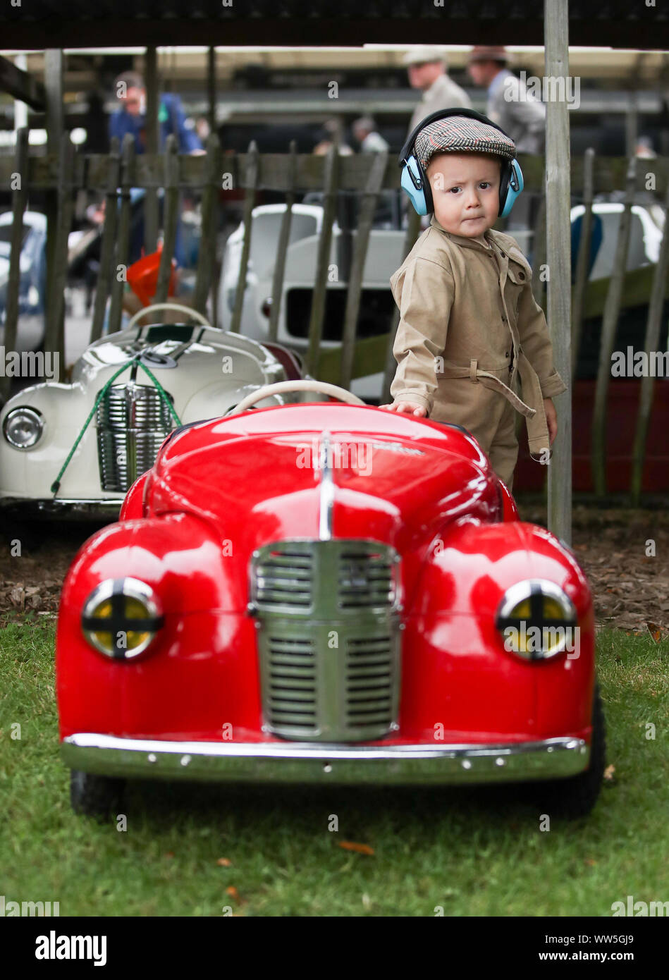 Walter, 3, from Kent, stnds next to his sister's Austin J40 pedal car, which she will drive in the Settringham Cup during the Goodwood Revival at the Goodwood Motor Circuit, in Chichester. Stock Photo