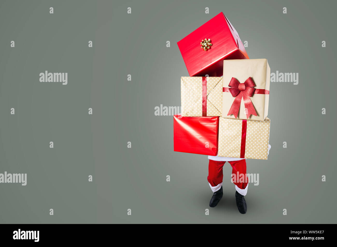 Santa Claus carrying a big stack of Christmas presents Stock Photo