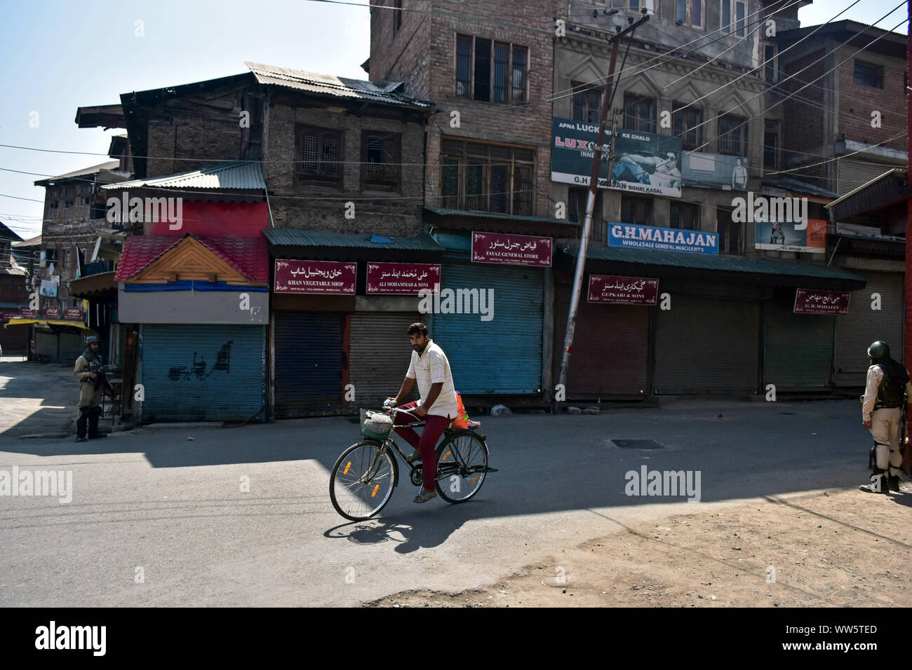 Kashmir, India. 13th Sep, 2019. A cyclist rides along a street as paramilitary troopers stand guard during shutdown in Srinagar, Kashmir. Kashmir valley remained shut for the 40th consecutive day following the scrapping of Article 370 by the central government which grants special status to Jammu & Kashmir. Credit: SOPA Images Limited/Alamy Live News Stock Photo
