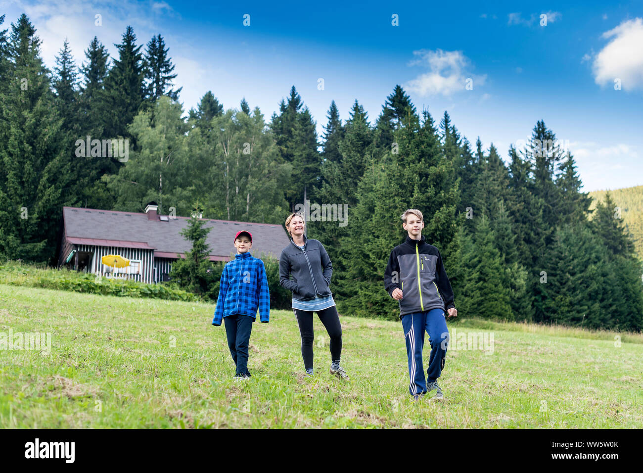 family of three walking in mountain countryside, mother with two sons strolling in mountain countryside Stock Photo