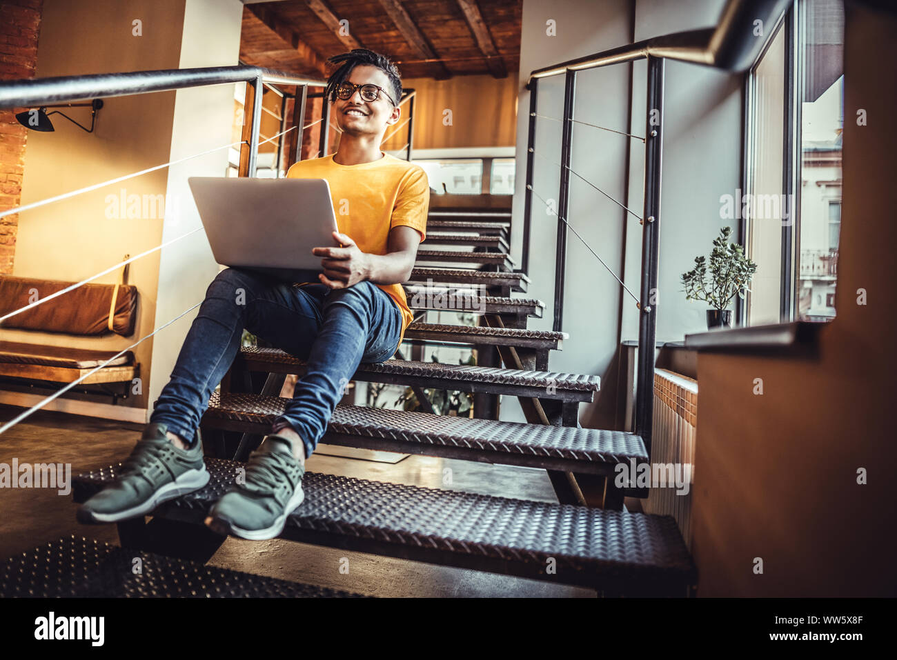 Smiling modern young man using gadgets at cafe. The concept of study, freelancing, work, technology. Stock Photo