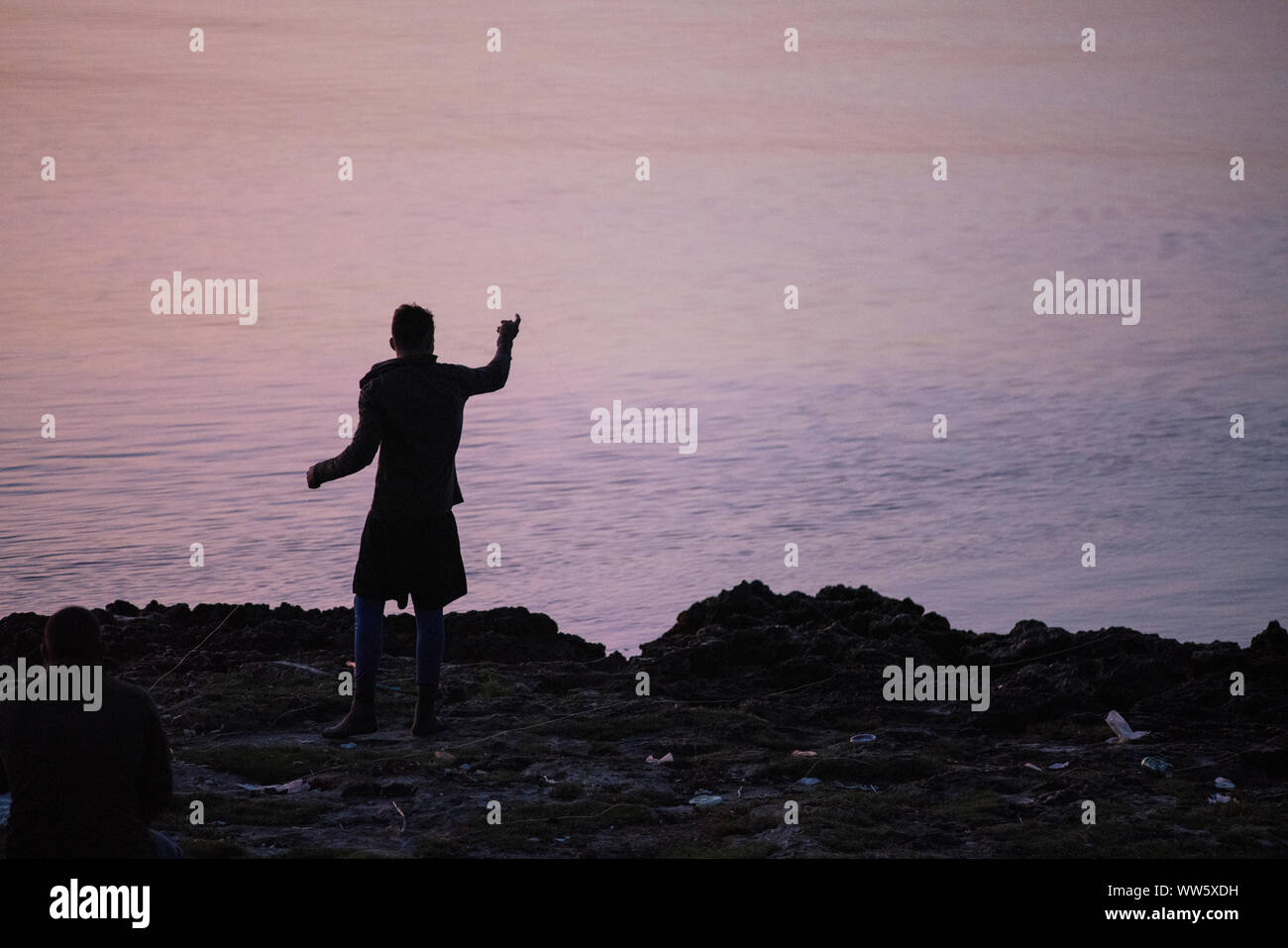 A man fishing from the shore, the water reflecting violet before sunrise, Playa Larga, Stock Photo