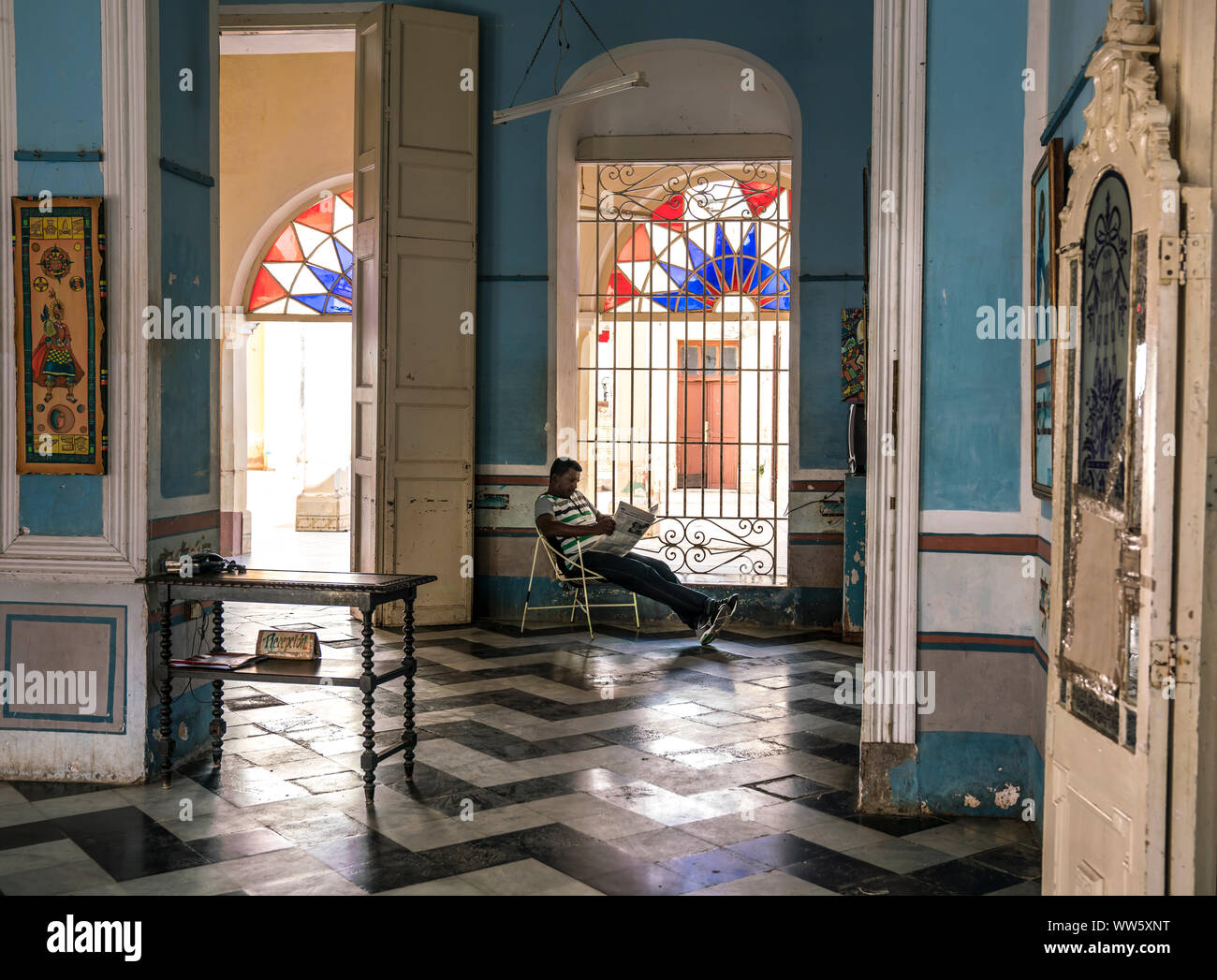 Man, 40-50 years old, sitting in a building in colonial style and reading newspaper Stock Photo