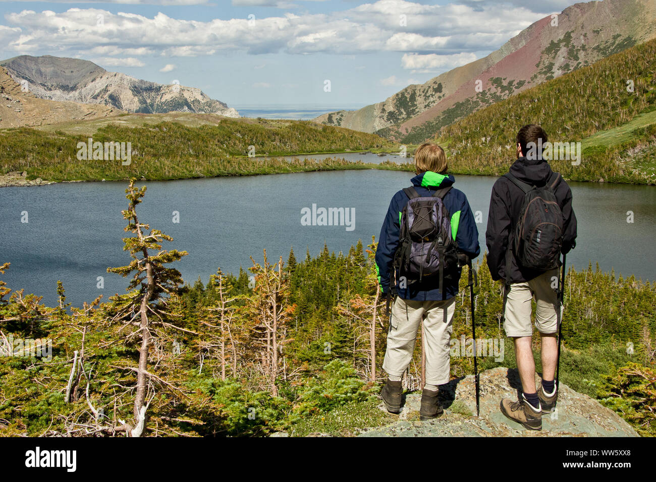 Two hikers looking at a lake in the Rocky Mountains and enjoying the breathtaking view, Canada Stock Photo