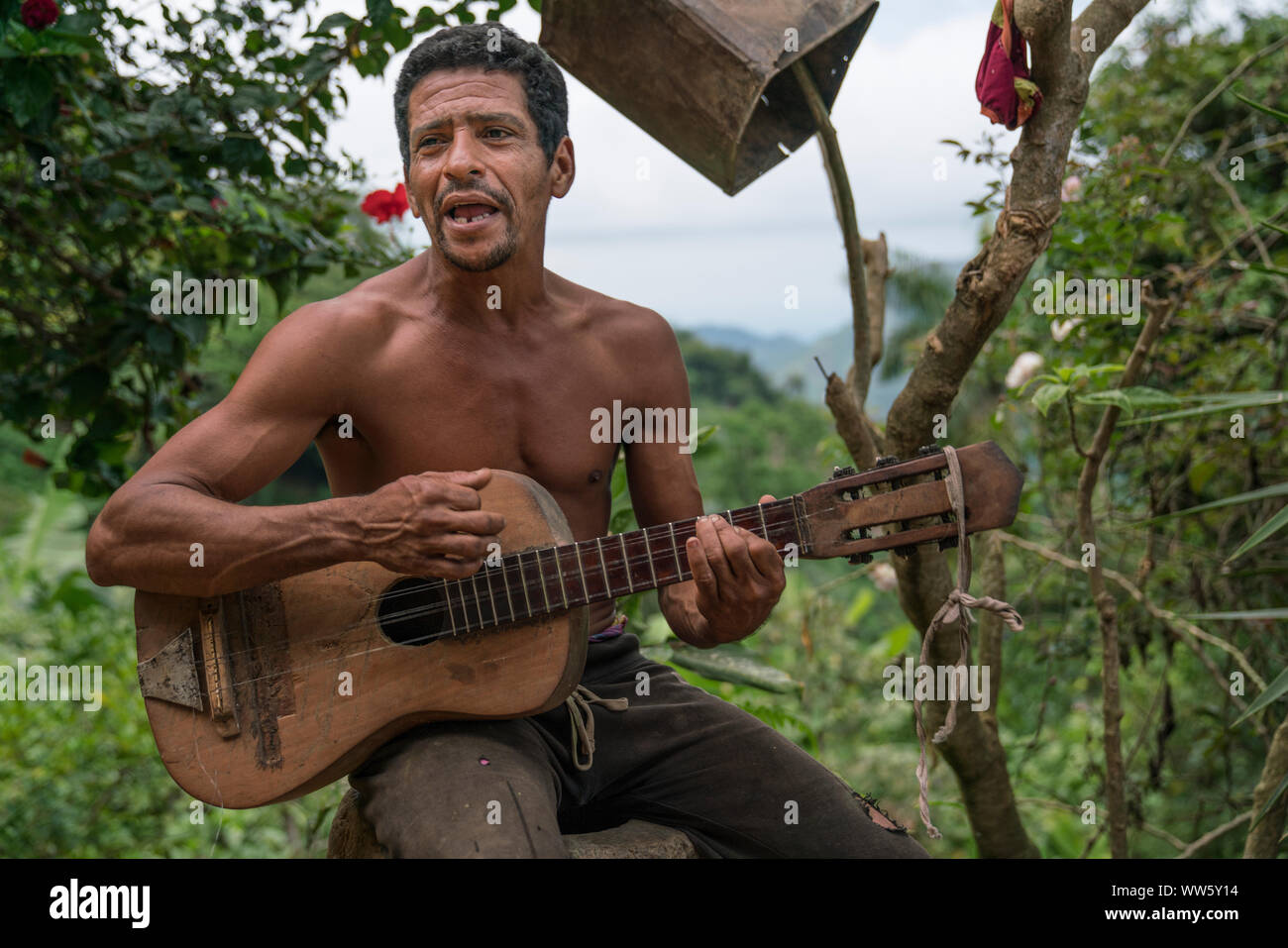 A man playimg on a self-built guitar, mountain farm in the Sierra Maestra Stock Photo