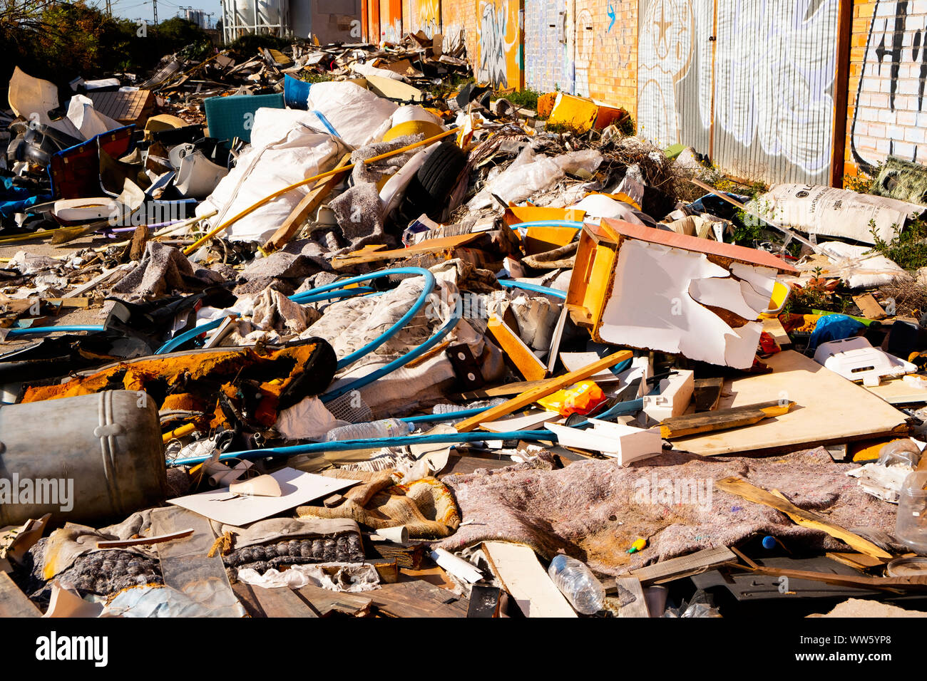 closeup of a pile of garbage illegally dumped in an open dump next to some abandoned warehouses Stock Photo