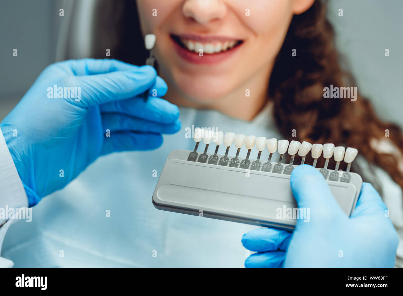 Dentist selecting patient's teeth color with palette in clinic, close up view. Stock Photo