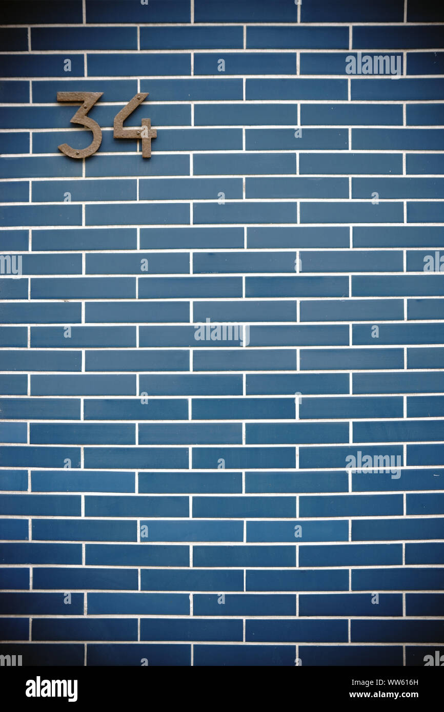 Nostalgic house number on striking blue clinker brick wall hires stock