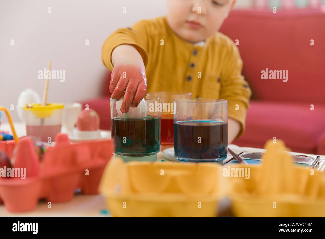 Toddler, dyeing Easter egg, hand in the glass Stock Photo Alamy