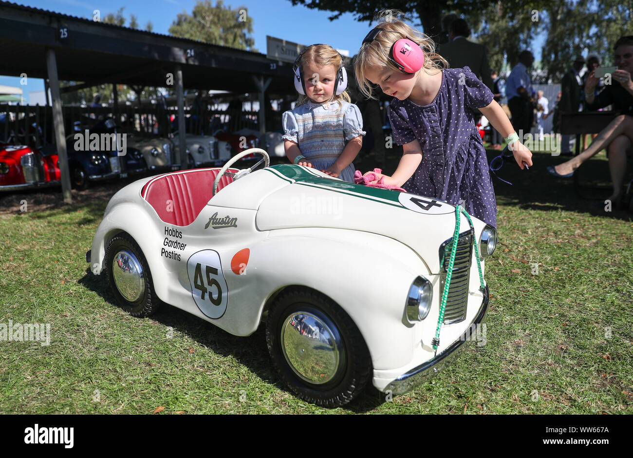 Poppy, six (right), and her sister Milly, three, from Gloucestershire, polish their Austin J40 pedal car ahead of Saturday's Settrington Cup, during day one of the Goodwood Revival at the Goodwood Motor Circuit, in Chichester. Stock Photo