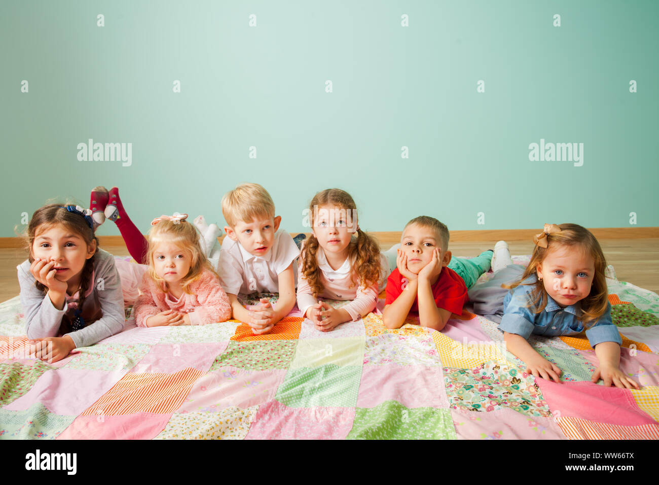 Group of six cute little kids, boys and girls of different age, laying