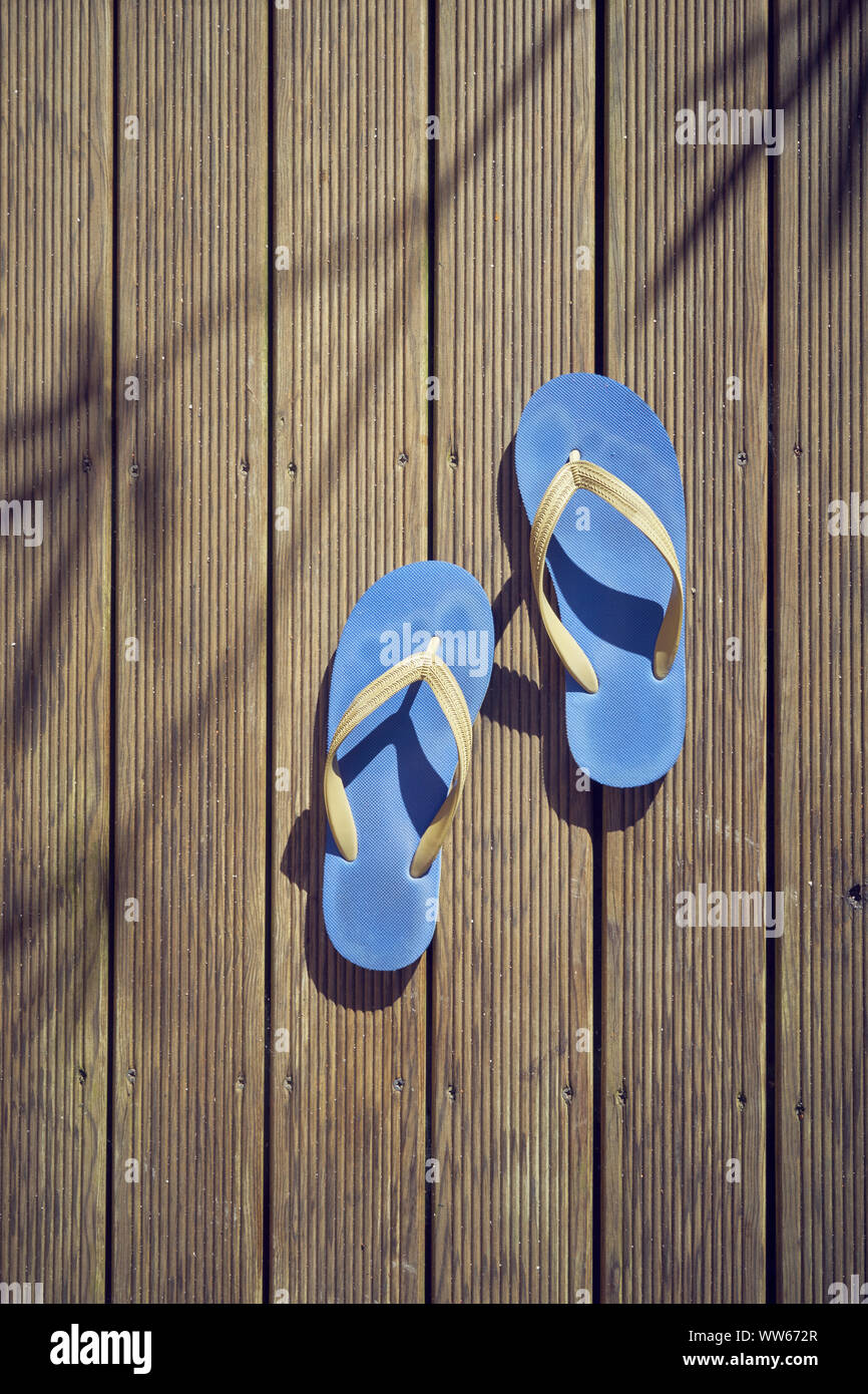 Blue flip flops on brown wood, from above, shadow of oleander Stock Photo