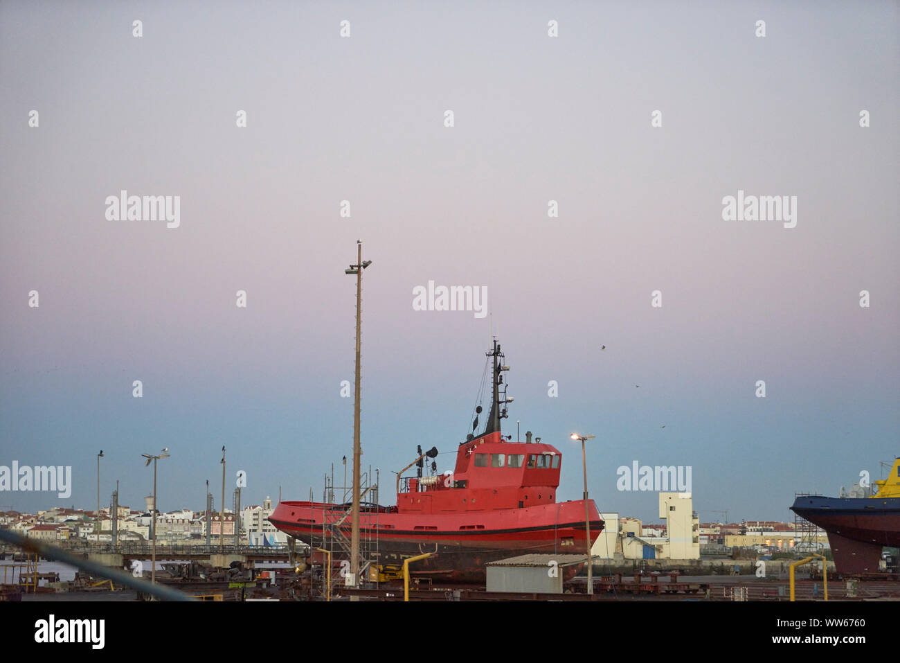 Red boat in a shipyard near the town in the harbour, sky Stock Photo