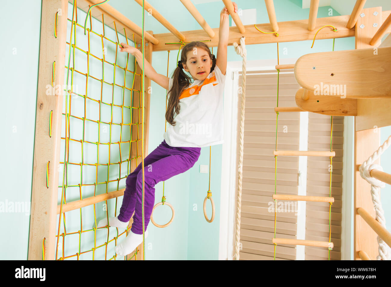 Adorable little girl climbing wooden bars and rope ladder at home sport gym. Small future gymnast girl training at home Stock Photo Alamy