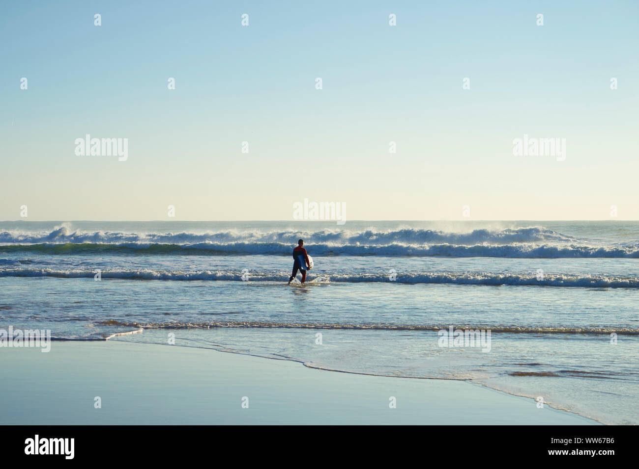 Man carrying surfboard in the sea, waves Stock Photo
