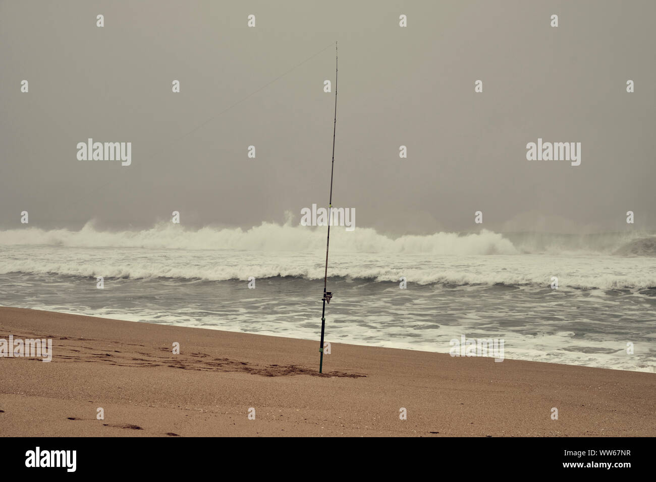 Fishing rod in the ground on the beach, sea, waves, surf, foam, Stock Photo