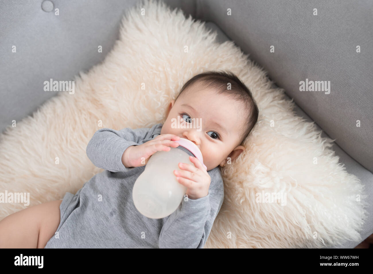 Asian baby infant eating milk from bottle, 9 months after birth Stock