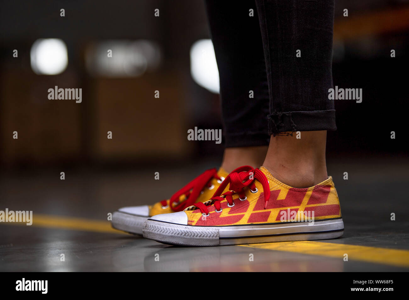 leeuwerik theater Assimilatie 13 September 2019, Lower Saxony, Langenhagen: One employee wears yellow  shoes with the red DHL logo at the opening of the new DHL freight terminal.  DHL opens a new freight terminal in