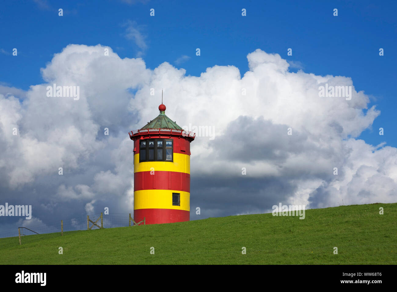 Swelling Cumulus clouds above the old Pilsum lighthouse in the East Frisian Krummhoern. Stock Photo