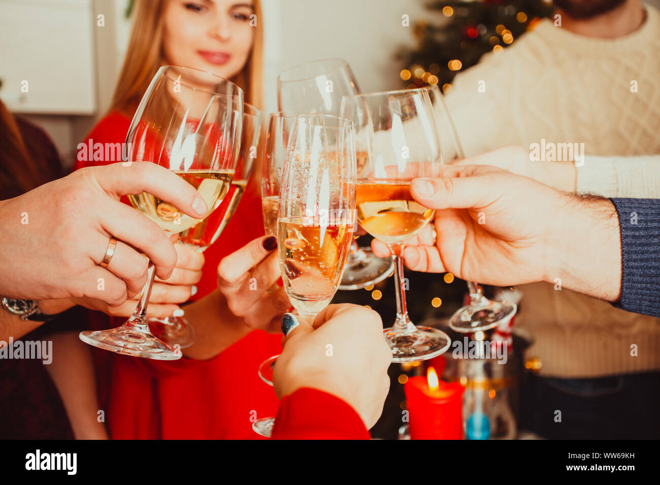 New year or Christmas party at home, brothers and sisters cheering wishing all the best to each other. Close view of hands of young people clinking ch Stock Photo
