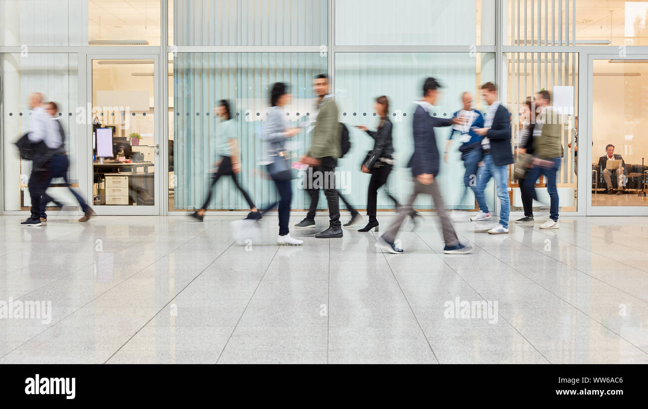 Many blurred people are walking through a modern office Stock Photo