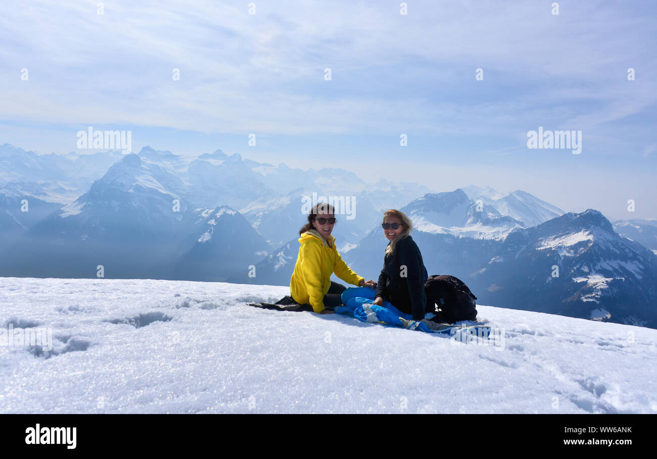 Two smiling women sitting on Fronalpstock mountain, Switzerland Stock Photo