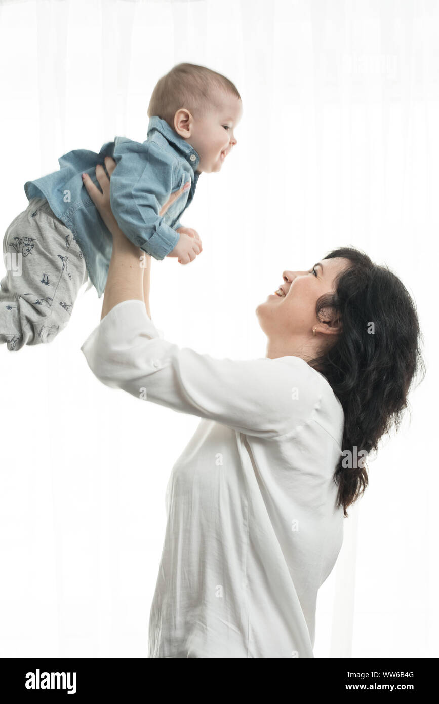 Mom throws up the baby in the apartment. Mom plays with her one year