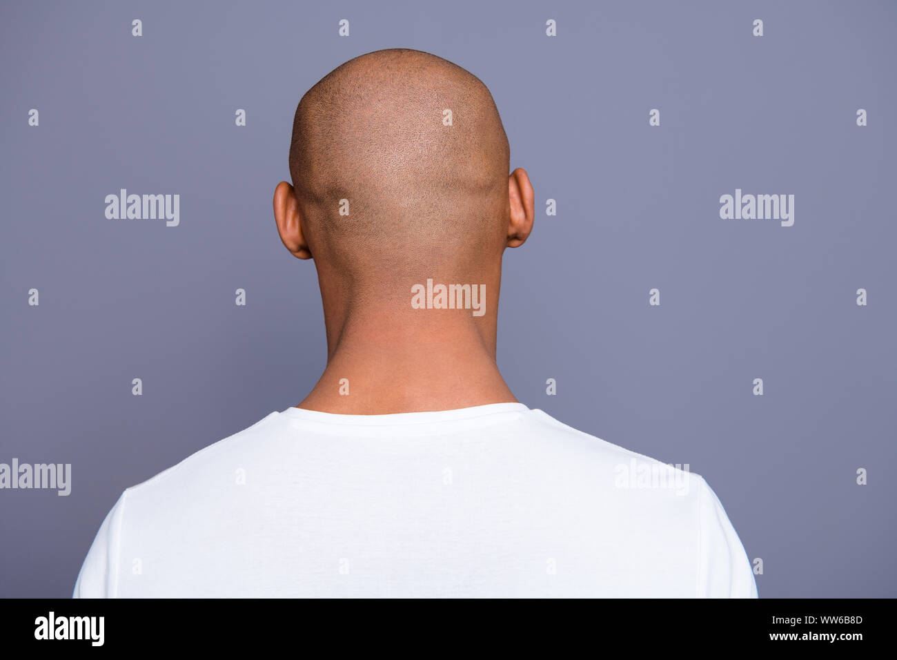 Close up back behind rear view photo dark skin he him his man turned to empty space distracted unrecognizable groomed shaved head wearing white t Stock Photo