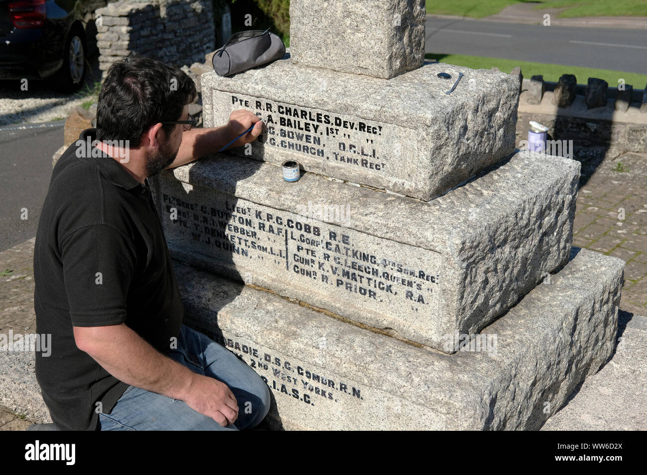 A sign writer, painter working on a war memorial in Chilcompton, Somerset. Stock Photo