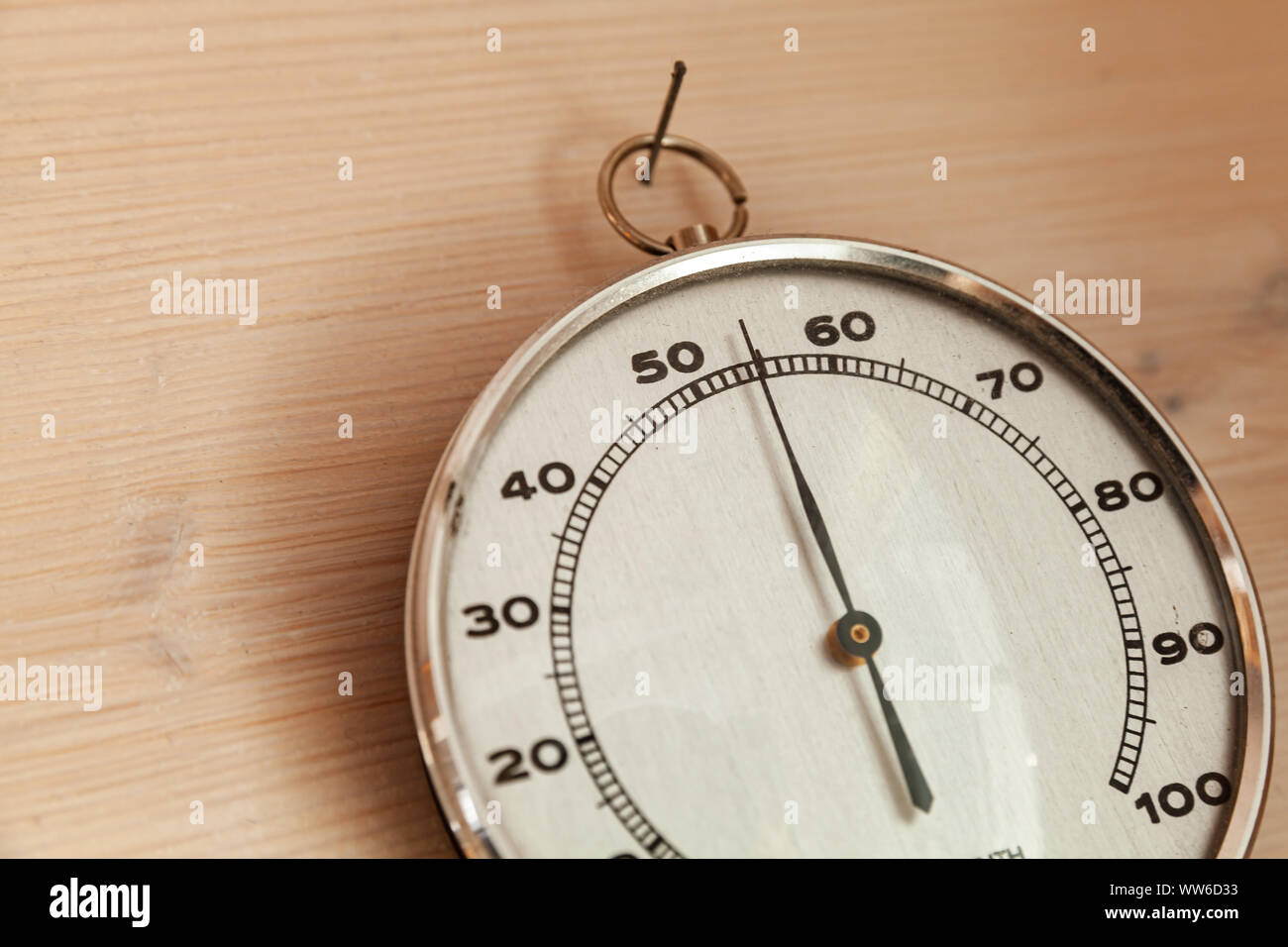 Analog hygrometer hanging on wooden wall, close-up photo. This hair tension instrument used to measure the amount of humidity and water vapour in the Stock Photo