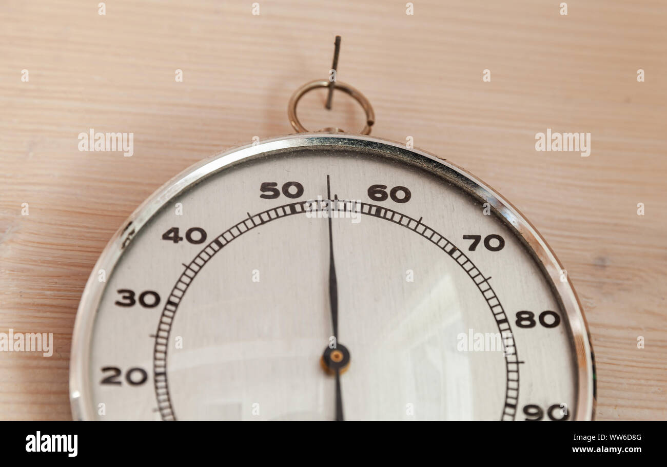 Analog hygrometer hanging on wooden wall, close-up photo. This instrument used to measure the amount of humidity and water vapour in the atmosphere Stock Photo