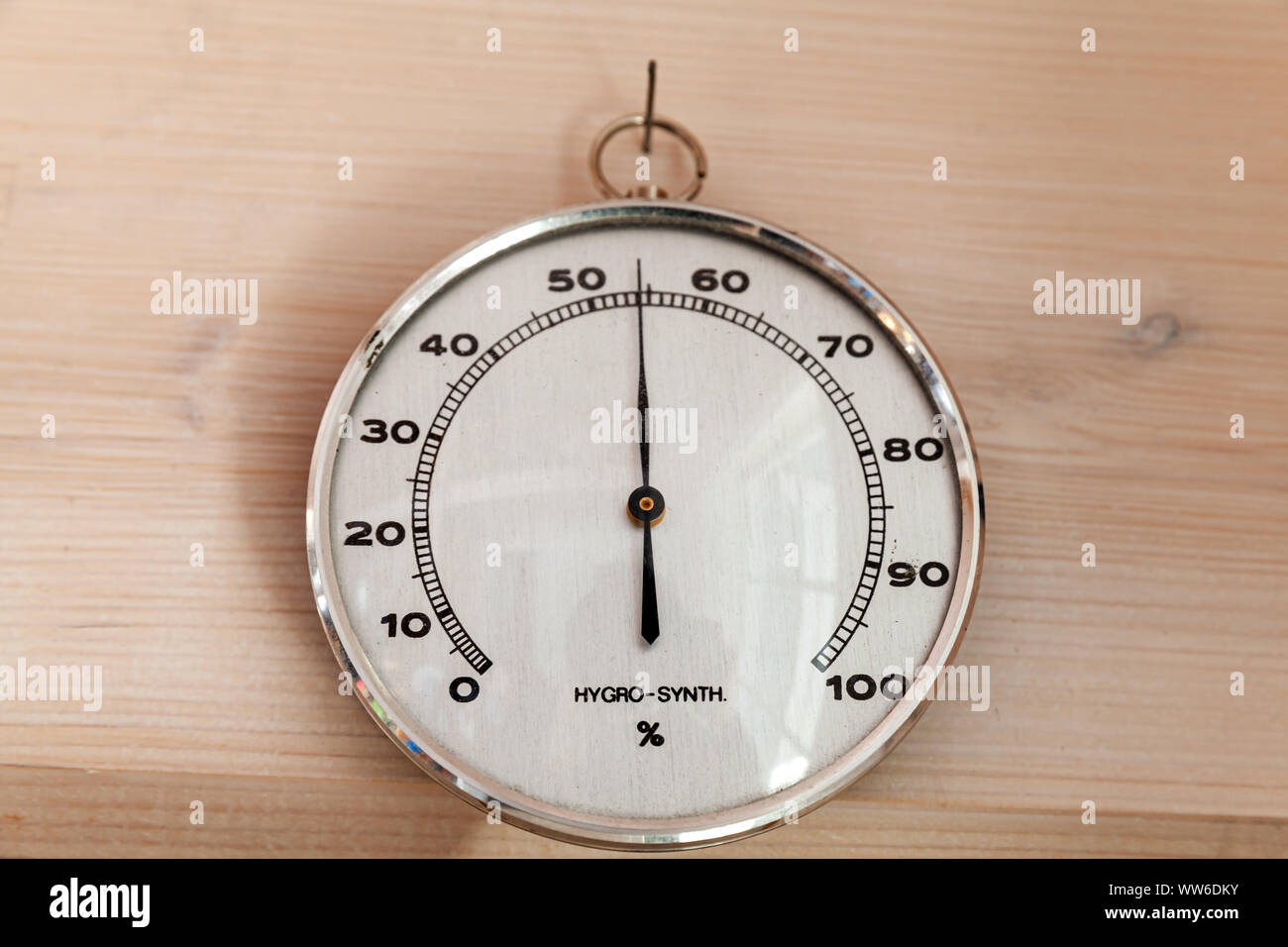 Analog Hygro Synth hygrometer hanging on wooden wall, close-up photo. This hair tension instrument used to measure the amount of humidity and water va Stock Photo