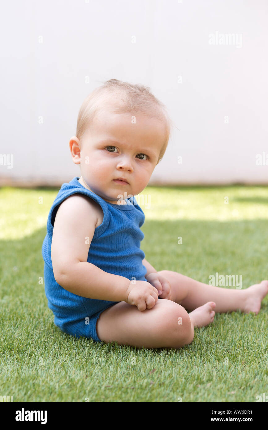 Baby is sitting in the grass, portrait Stock Photo