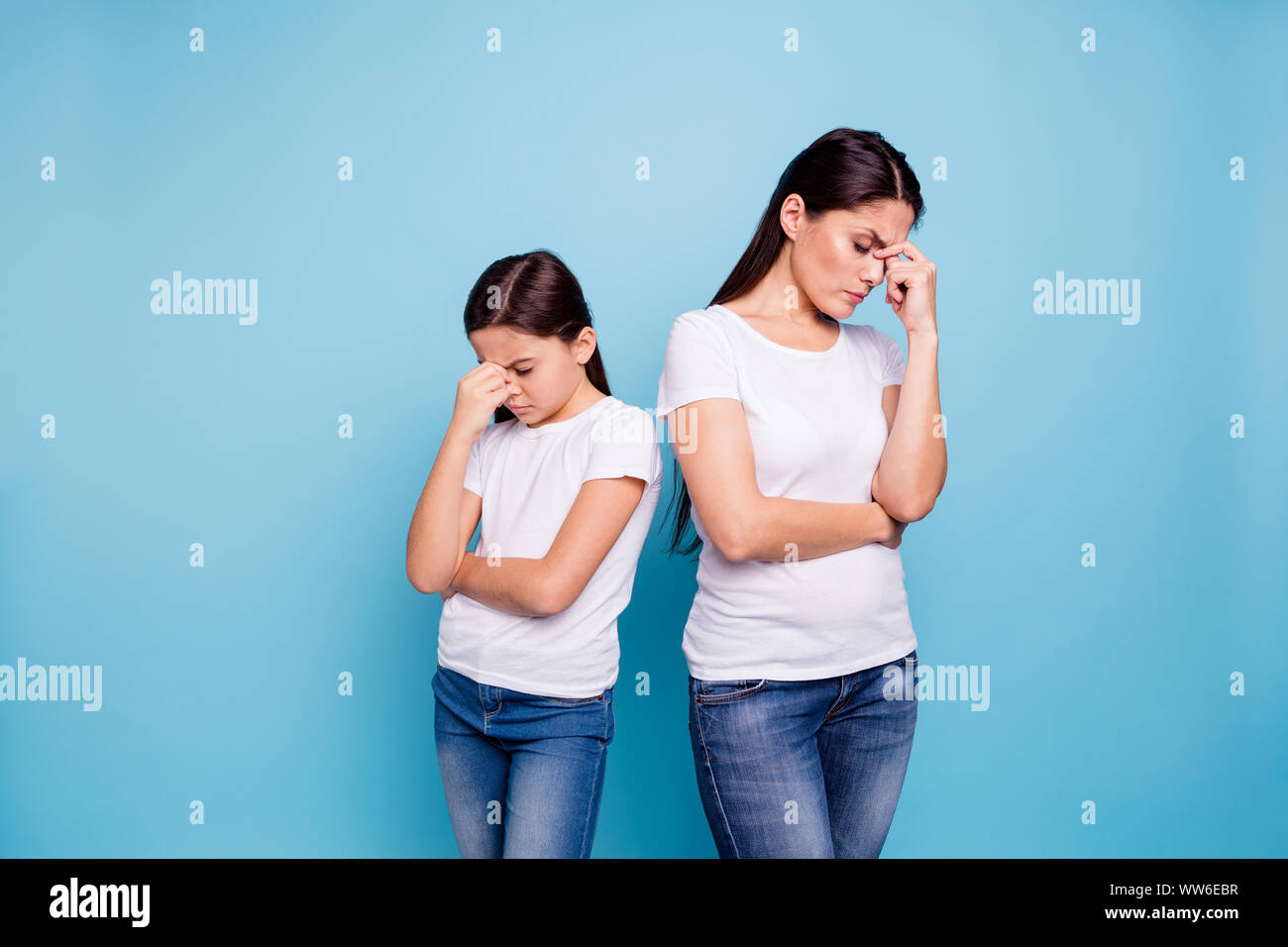 Close up photo two people brown haired mum disinterested small little daughter hand on face sick and tired sorry blaming eyes closed wear white t Stock Photo