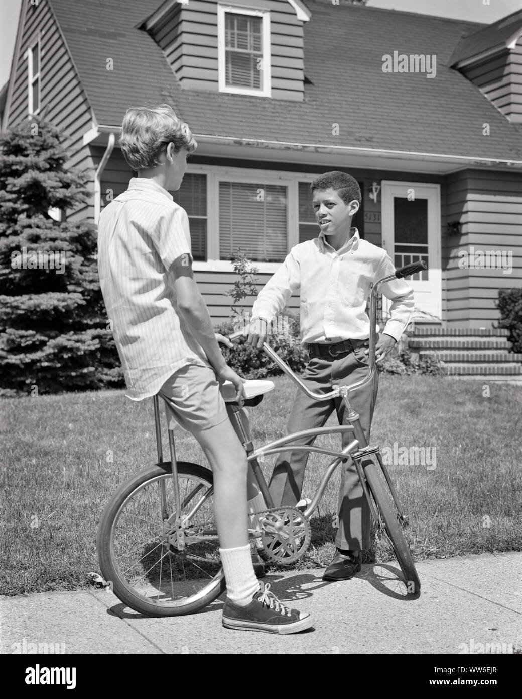 1960s 1970s TWO PRETEEN BOYS ONE AFRICAN AMERICAN AND THE OTHER CAUCASIAN WITH BICYCLE TALKING TOGETHER ON SUBURBAN SIDEWALK - b23982 HAR001 HARS RACIAL MALES TEENAGE BOY BICYCLES TRANSPORTATION B&W BIKES NEIGHBORS NEIGHBORHOOD AFRICAN-AMERICANS AFRICAN-AMERICAN AND BLACK ETHNICITY FRIENDLY RACE RELATIONS JUVENILES PRE-TEEN PRE-TEEN BOY BLACK AND WHITE BUDDIES CAUCASIAN ETHNICITY HAR001 OLD FASHIONED AFRICAN AMERICANS Stock Photo