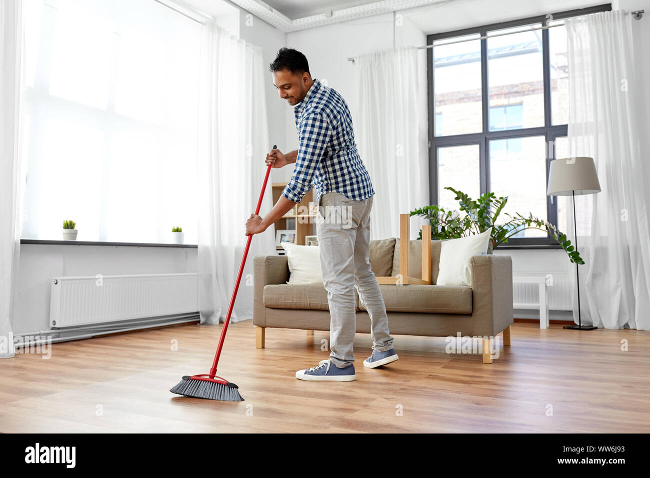 man with broom cleaning floor at home Stock Photo