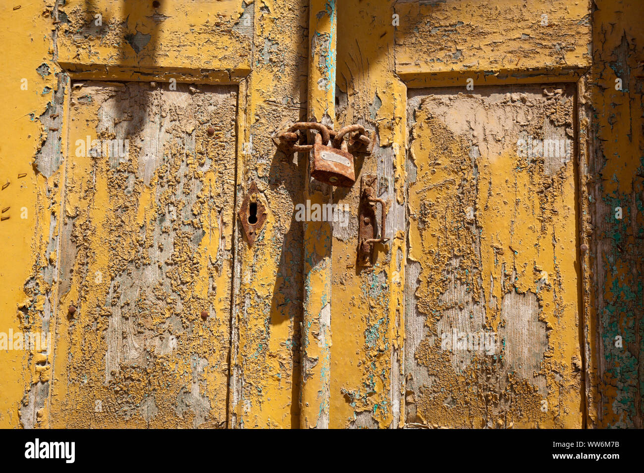 Wooden door with padlock and weathered yellow paint in greece hires