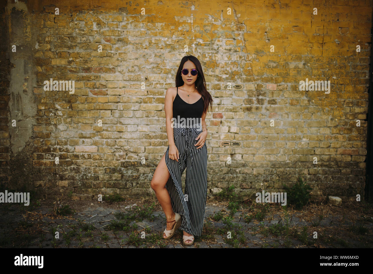 Portrait of a young woman standing in front of a brick wall Stock Photo ...