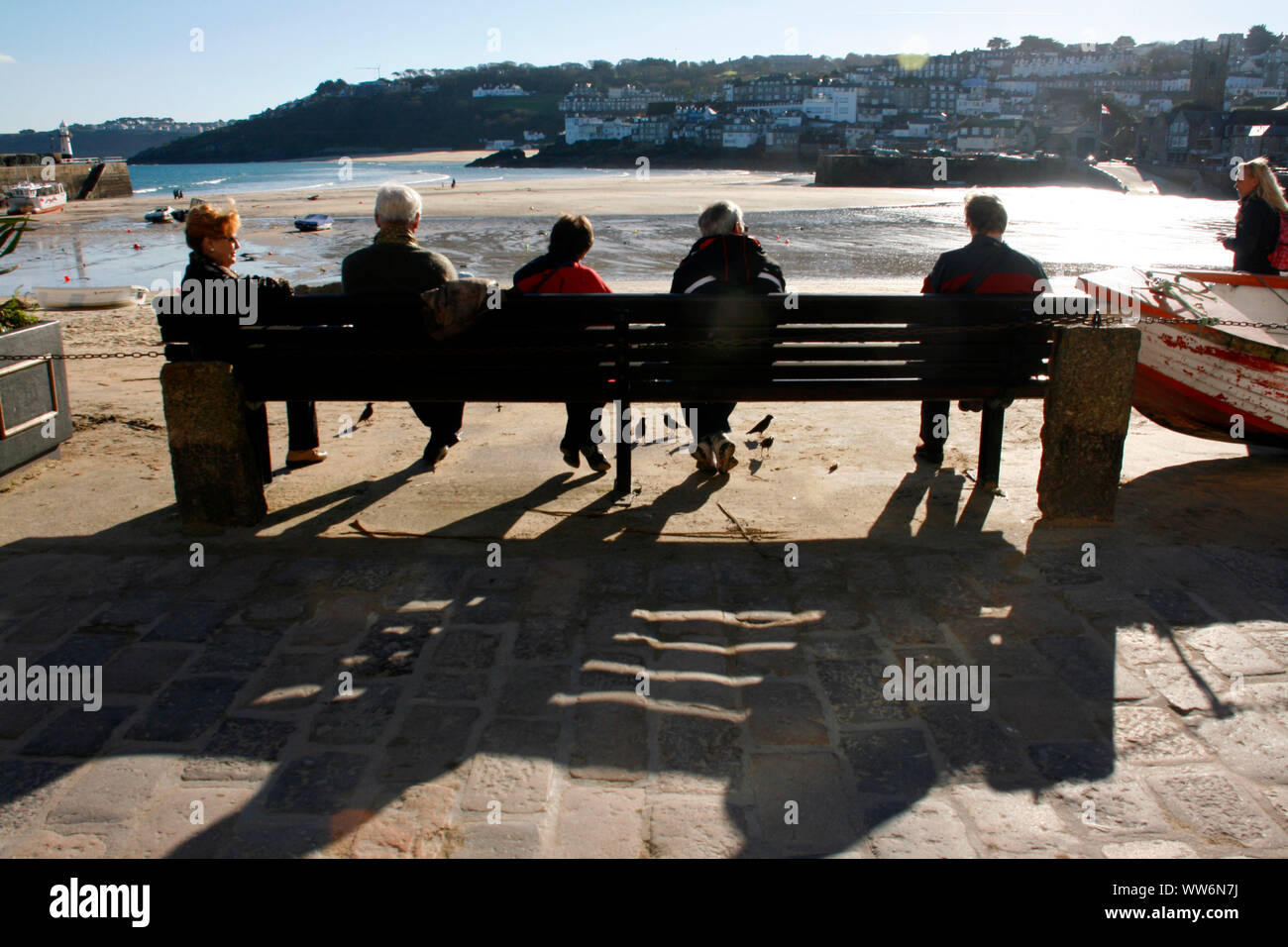 five people sitting on an bench in St Ives Cornwall Stock Photo