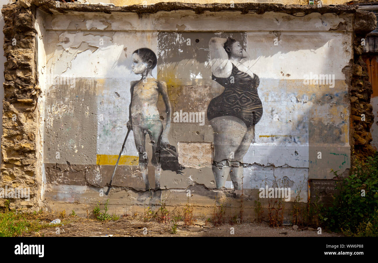 faded mural painting of a boy and a woman in bathing costume on ruin property in Greece Stock Photo
