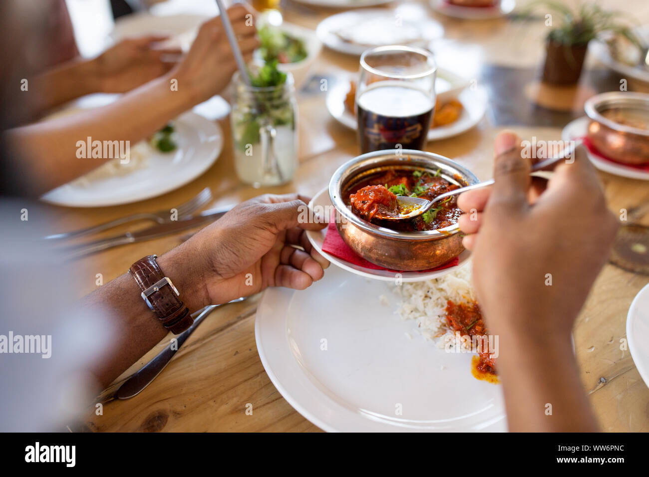 african man eating with friends at restaurant Stock Photo