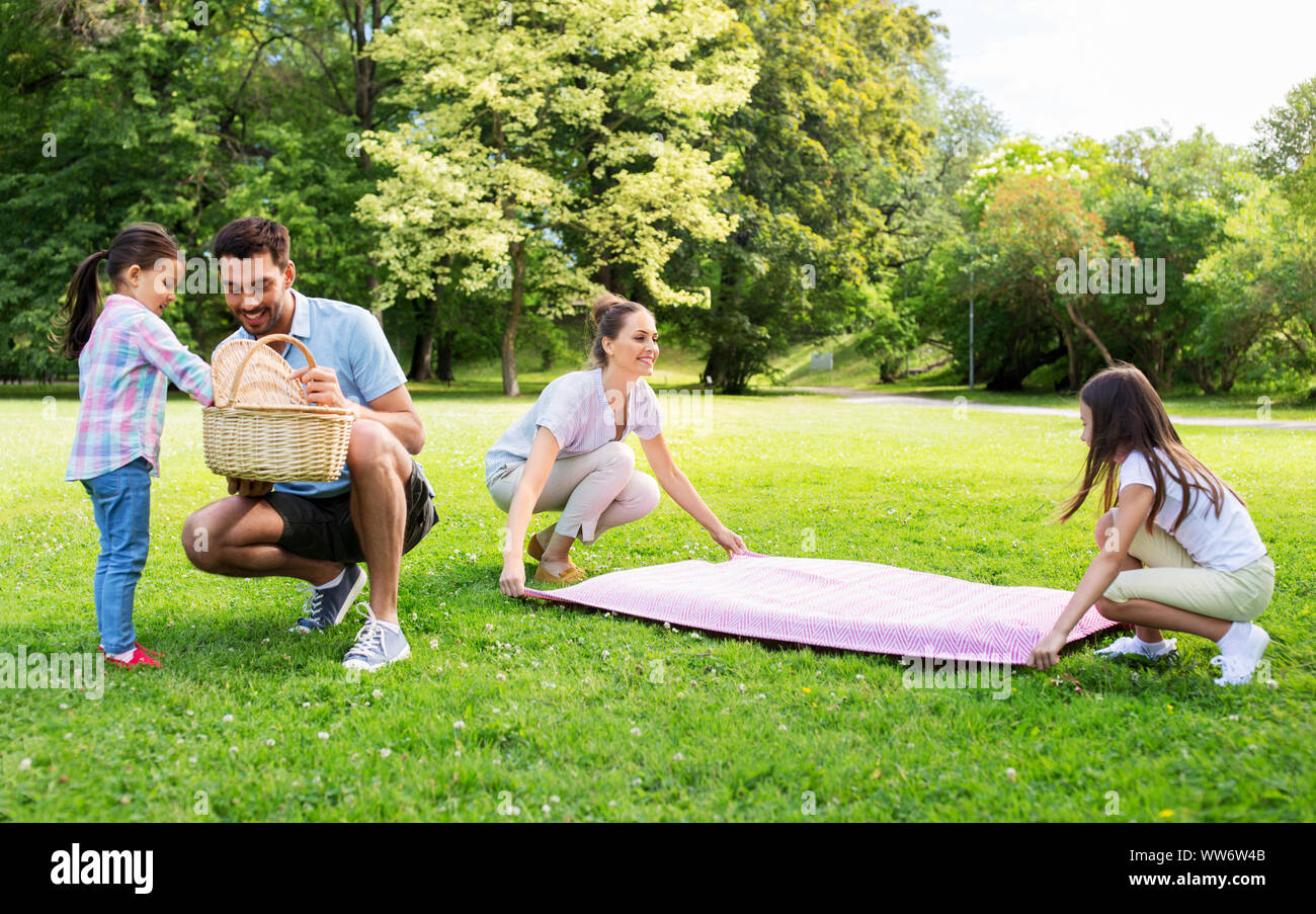 family laying down picnic blanket in summer park Stock Photo Alamy