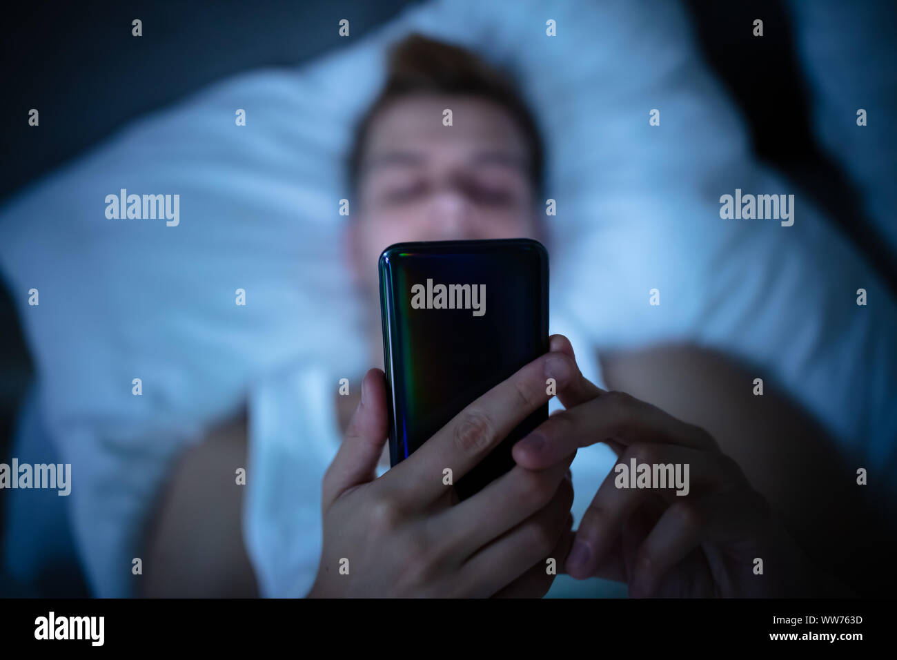 Man In Bed With Mobile Phone At Night Stock Photo